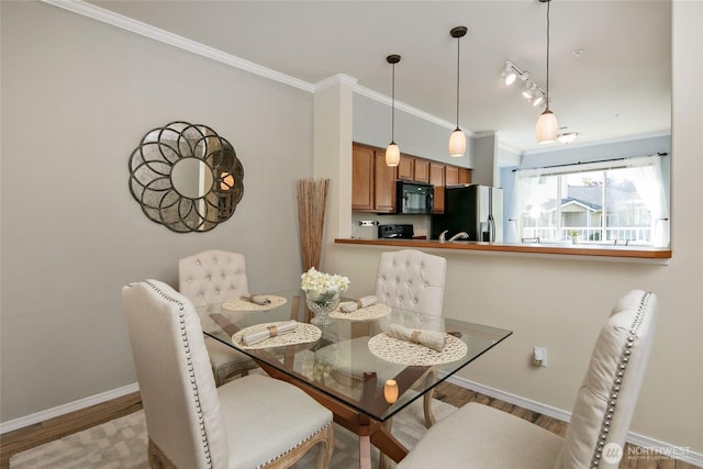 dining room featuring crown molding, baseboards, and wood finished floors
