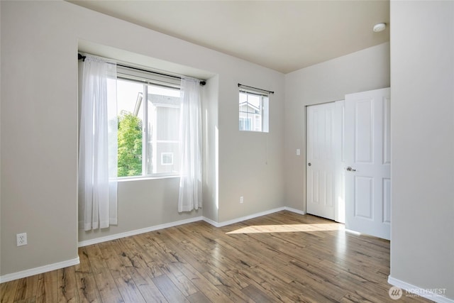 unfurnished room with baseboards and wood-type flooring