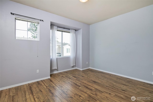 spare room with baseboards and wood finished floors