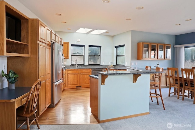 1491 Olympic Heights Ln, Freeland, WA 98249 - kitchen with a breakfast bar area, a skylight, a sink, dark stone countertops, and glass insert cabinets