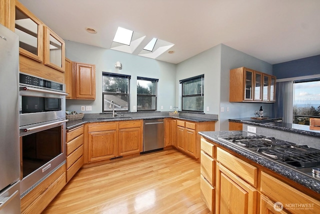 1491 Olympic Heights Ln, Freeland, WA 98249 - kitchen featuring glass insert cabinets, a sink, light wood finished floors, appliances with stainless steel finishes, and a skylight