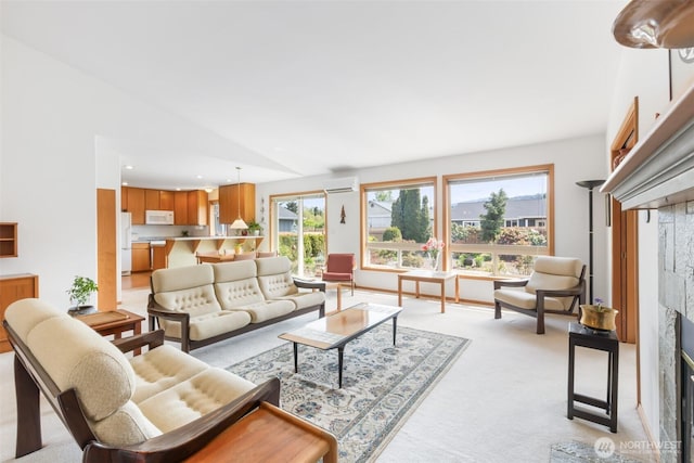 living area featuring a glass covered fireplace, light carpet, vaulted ceiling, and a wall mounted air conditioner