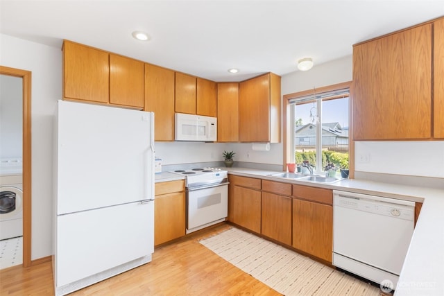 kitchen featuring washer / clothes dryer, a sink, light countertops, white appliances, and light wood-style flooring