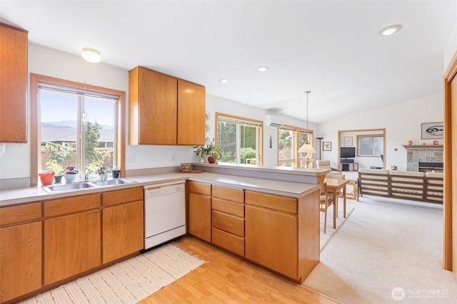 kitchen with white dishwasher, light countertops, a peninsula, and a sink