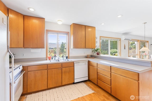 kitchen featuring a peninsula, white appliances, an AC wall unit, light countertops, and light wood-style flooring