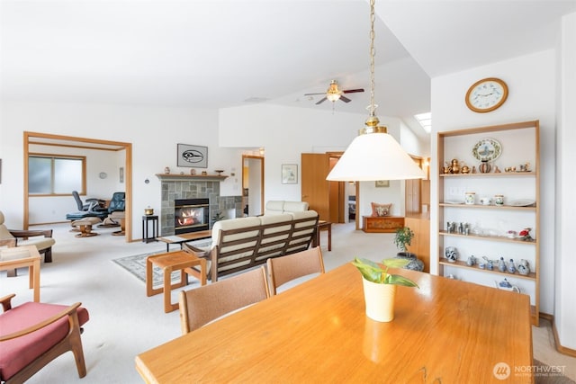 dining room featuring a ceiling fan, carpet, a glass covered fireplace, and vaulted ceiling