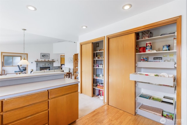 kitchen featuring light countertops, open shelves, pendant lighting, and a fireplace
