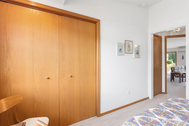 bedroom featuring baseboards, light colored carpet, and a closet