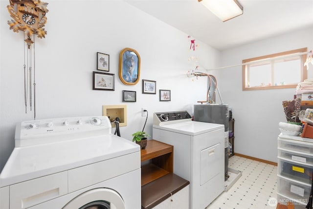 washroom with laundry area, washing machine and dryer, baseboards, light floors, and water heater