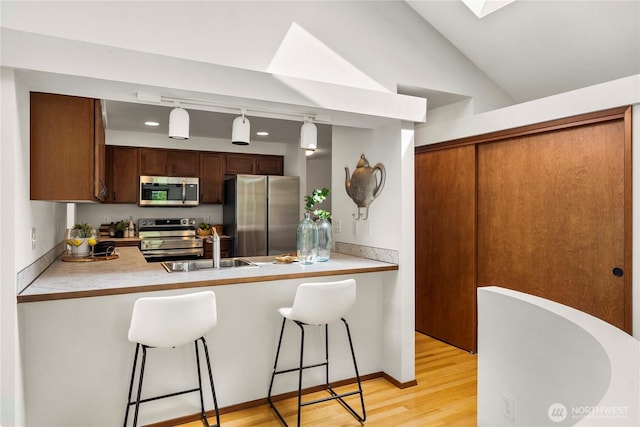 11815 77th Ave S, Seattle, WA 98178 - kitchen with stainless steel appliances, a sink, a peninsula, light wood finished floors, and a breakfast bar