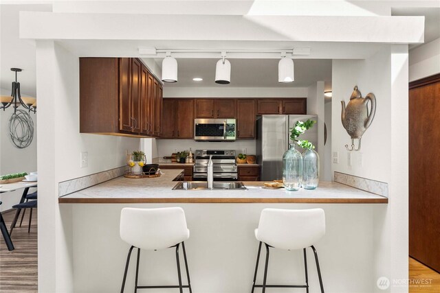 11815 77th Ave S, Seattle, WA 98178 - kitchen featuring stainless steel appliances, a peninsula, a breakfast bar area, and light countertops