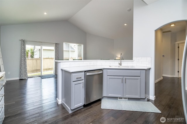 kitchen with dishwasher, a sink, arched walkways, a peninsula, and light countertops