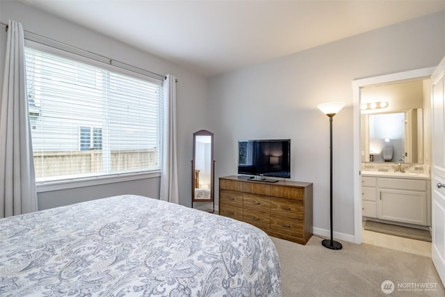 carpeted bedroom with a sink, ensuite bath, and baseboards