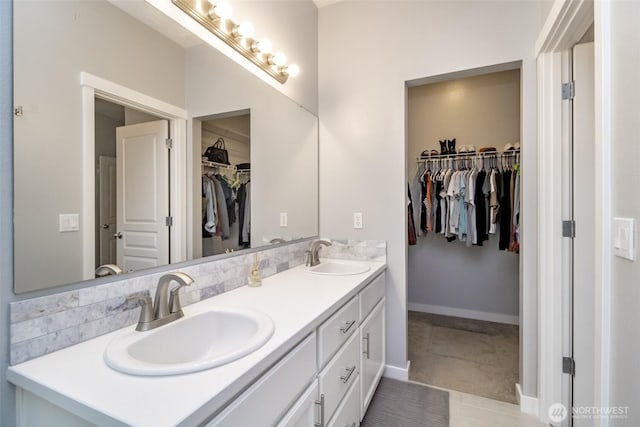 bathroom featuring double vanity, a spacious closet, baseboards, and tile patterned floors