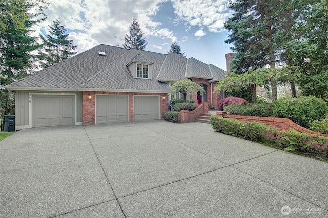 view of front of home featuring concrete driveway, brick siding, a chimney, and a garage