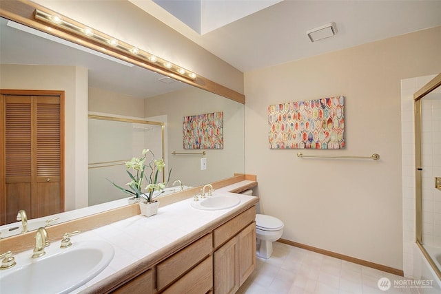 full bath featuring double vanity, a sink, an enclosed shower, and toilet