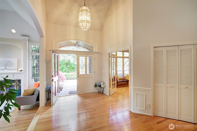 entrance foyer with a notable chandelier, a wealth of natural light, light wood finished floors, and a decorative wall