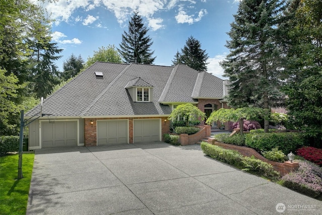 view of front facade with brick siding, an attached garage, and driveway