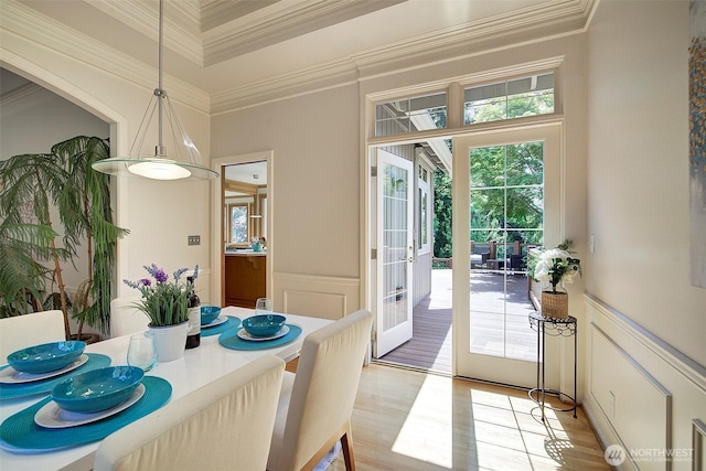 dining space with plenty of natural light, ornamental molding, a decorative wall, and french doors