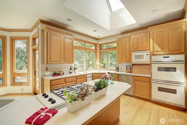 kitchen with white appliances, a skylight, light wood-style flooring, and light countertops