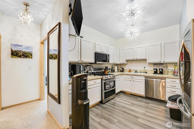 825 Harrington Pl SE Unit 2145, Renton, WA 98058 - kitchen with stainless steel appliances, a chandelier, light countertops, white cabinets, and baseboards