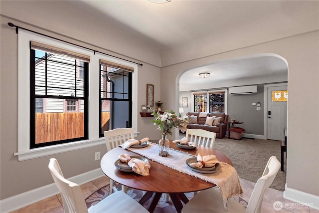 dining area with baseboards, arched walkways, and a wall mounted AC