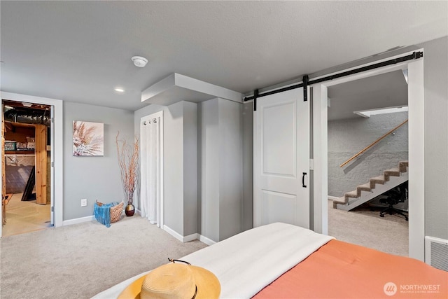bedroom featuring visible vents, a barn door, baseboards, and light carpet