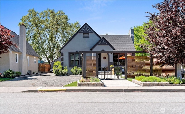 view of front of house featuring a chimney, a gate, fence private yard, and stucco siding