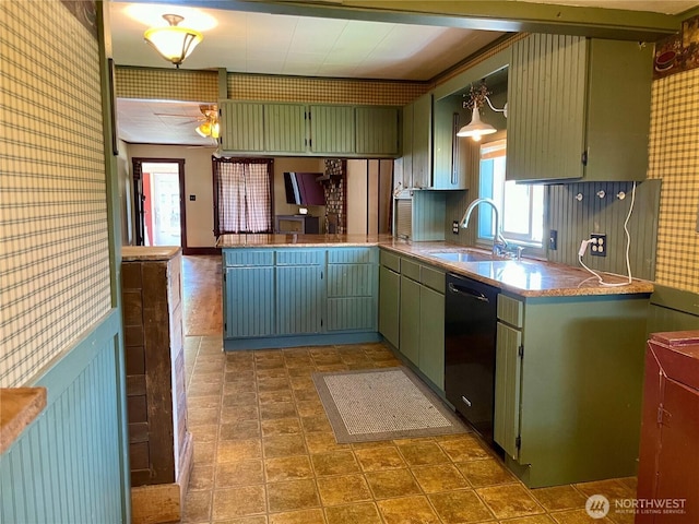 kitchen with a sink, green cabinetry, black dishwasher, and wallpapered walls