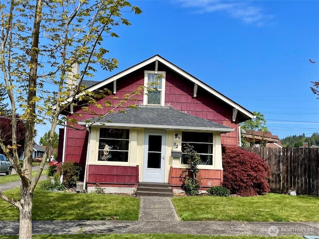 bungalow featuring roof with shingles, fence, a front yard, and entry steps