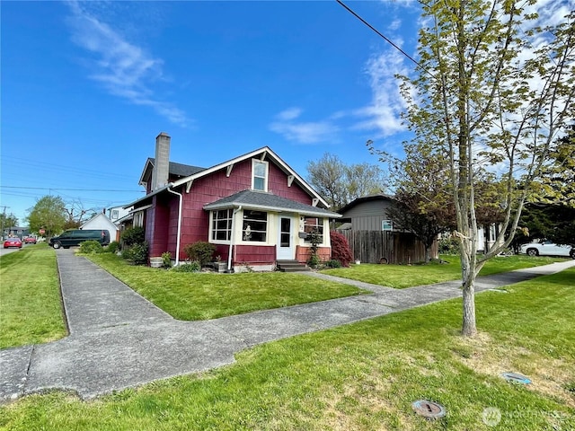 view of front of home featuring fence, a front yard, a chimney, and entry steps