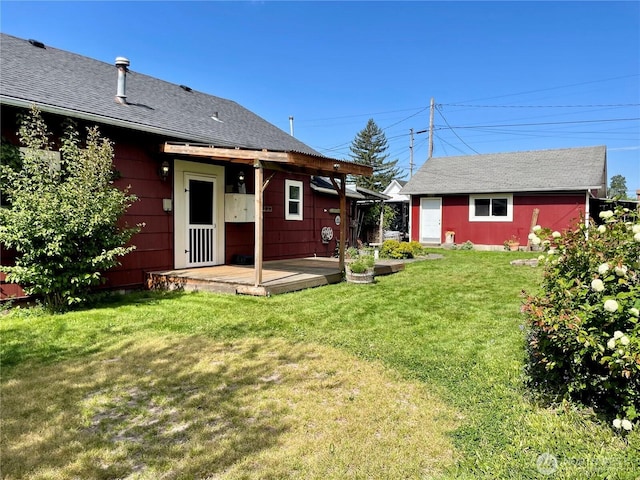 rear view of property with a yard and roof with shingles