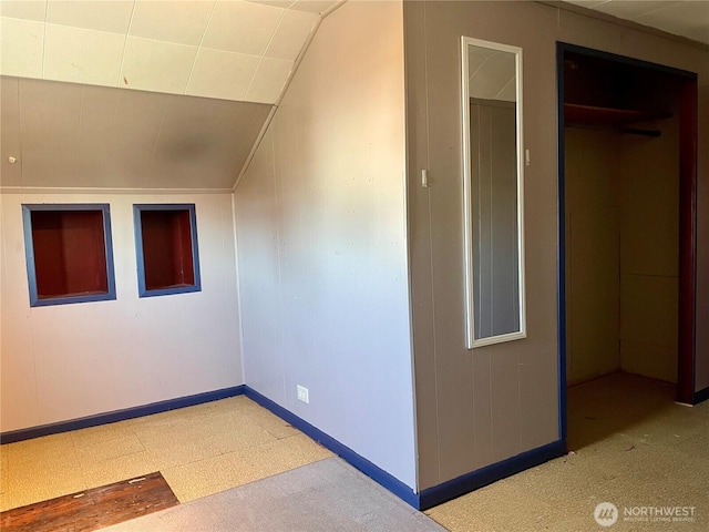 additional living space with baseboards and vaulted ceiling