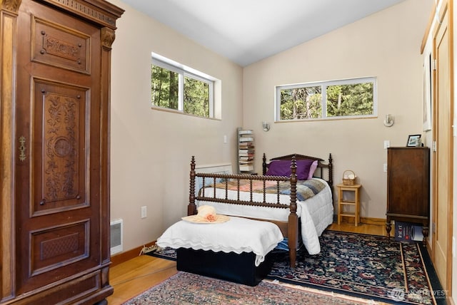 bedroom with baseboards, visible vents, lofted ceiling, and light wood-style floors