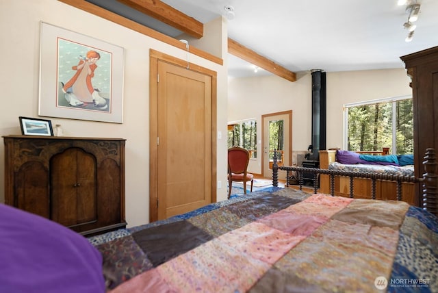 bedroom with a wood stove and beam ceiling