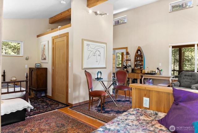 living room featuring wood finished floors, high vaulted ceiling, and beamed ceiling