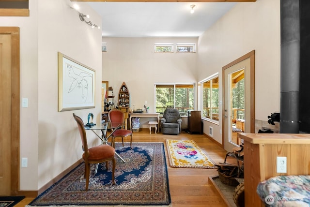 living area with a high ceiling, visible vents, and wood finished floors