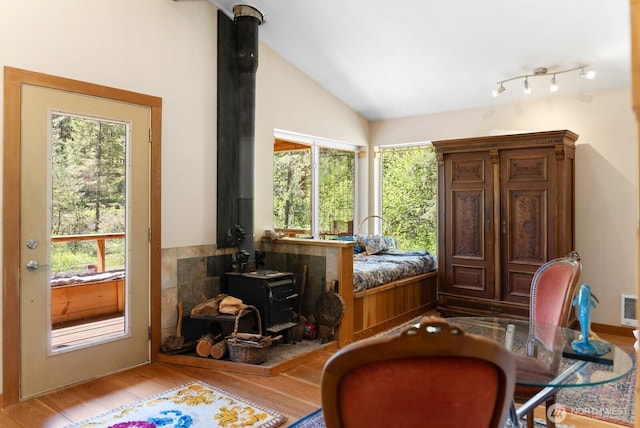 living area featuring visible vents, a wood stove, light wood-style flooring, and lofted ceiling