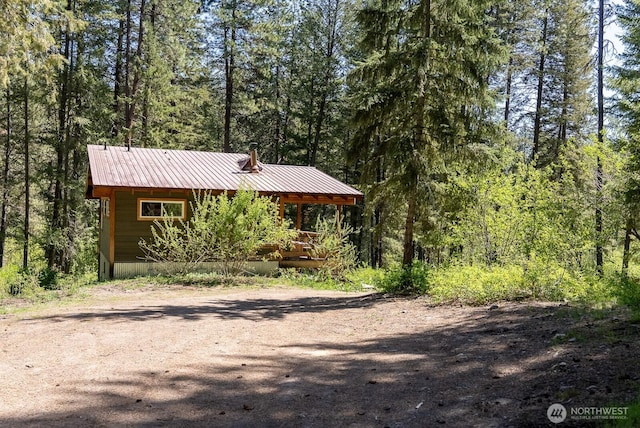 exterior space featuring metal roof and a forest view