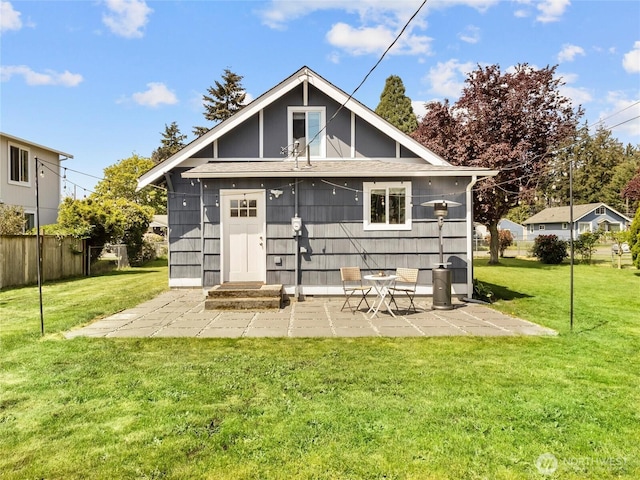 back of property with roof with shingles and a patio area