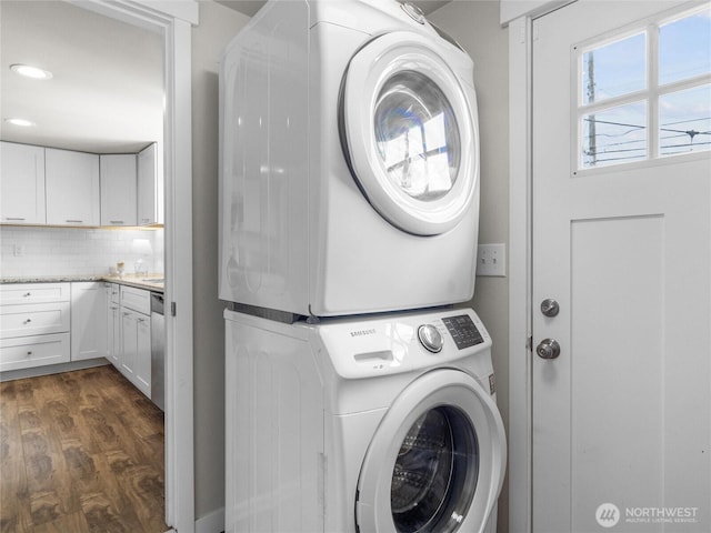 clothes washing area featuring stacked washing machine and dryer, dark wood-type flooring, and recessed lighting