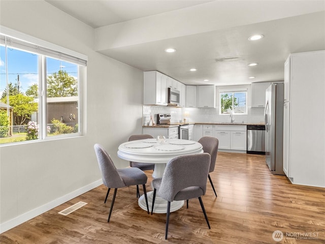 dining space with wood finished floors, baseboards, and recessed lighting