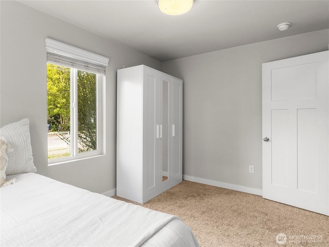 bedroom with light colored carpet and baseboards