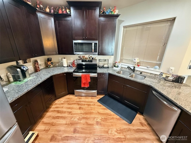 1755 E Madera St, Othello, WA 99344 - kitchen with dark brown cabinets, light stone countertops, appliances with stainless steel finishes, a sink, and light wood finished floors