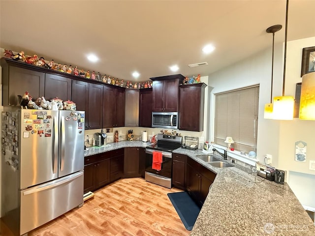 1755 E Madera St, Othello, WA 99344 - kitchen with visible vents, dark brown cabinets, a sink, light wood finished floors, and stainless steel appliances