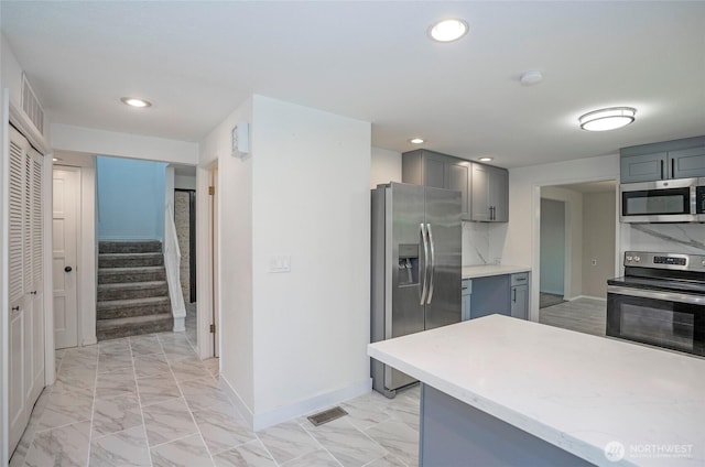 kitchen with stainless steel appliances, gray cabinetry, light marble finish floors, baseboards, and recessed lighting