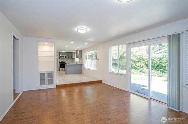 unfurnished living room with wood finished floors, baseboards, and recessed lighting