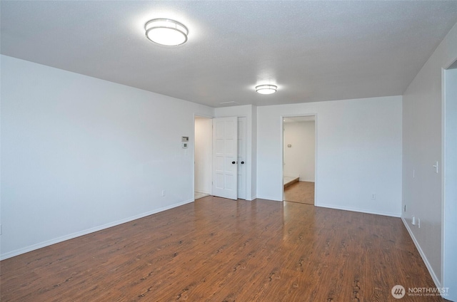 unfurnished room featuring dark wood-style floors and baseboards