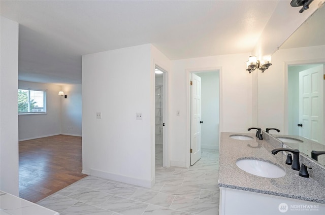 bathroom with baseboards, double vanity, and marble look tiles