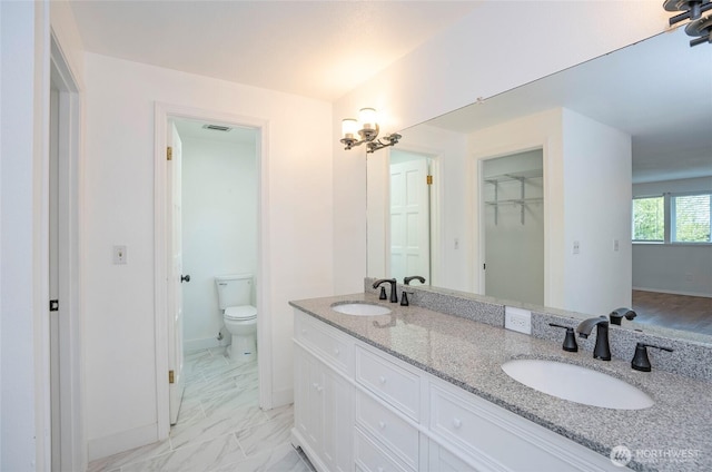 full bathroom with toilet, double vanity, marble finish floors, and baseboards